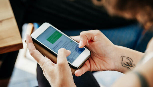 A close up of a woman messaging her friends using her smartphone in a cafe.